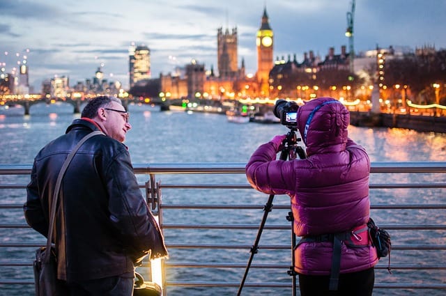 A photographer photographing on the banks of the Thames, London, with a companion looking on