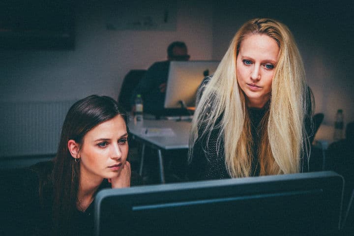 Two women sitting at a computer in an office